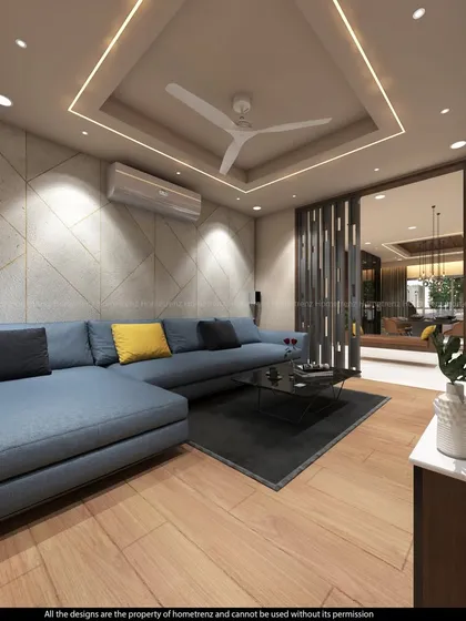 This living room is designed for comfort and conversation. The large blue sectional sofa provides ample seating, while the wood flooring and textured accent wall add warmth and character.