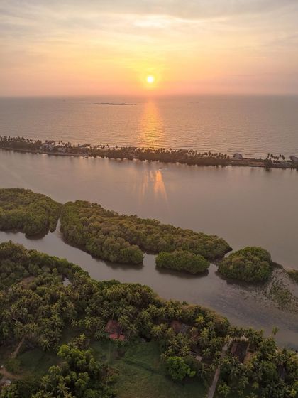 The beautiful coastline of Tulunadu at sunset. This drone shot captures the mangrove forests, the river, and the thin strip of land separating it from the Arabian Sea.