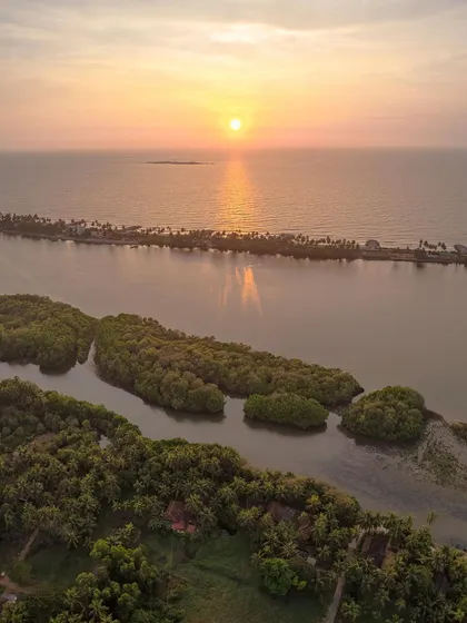 The beautiful coastline of Tulunadu at sunset. This drone shot captures the mangrove forests, the river, and the thin strip of land separating it from the Arabian Sea.