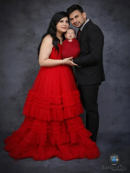 For a more formal family portrait, I offer sessions with dramatic lighting and elegant attire. The mother's stunning red gown and the baby's matching red swaddle create a striking and memorable image.
