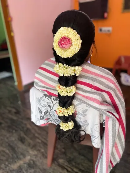 A classic South Indian bridal braid adorned with jasmine flowers and a central rose. This is a beautiful and traditional choice for a Muhurtham or engagement ceremony.