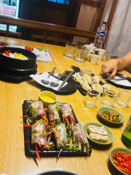 A spread of delicious Korean food, including bibimbap, spring rolls, and various side dishes (banchan).