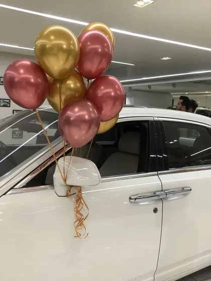Even a small touch can make a difference. A simple bouquet of chrome gold and rose gold balloons tied to a car's side mirror adds a festive detail to the showroom display.