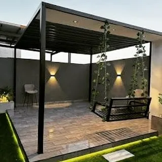 A sleek, modern pergola featuring a hanging swing bench. The design is enhanced by subtle LED strip lighting around the base and up-and-down sconces on the back wall for a contemporary feel.