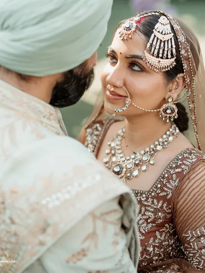 A close-up shot capturing the loving gaze between the bride and groom. This intimate portrait highlights the bride's beautiful jewelry and the deep connection they share.