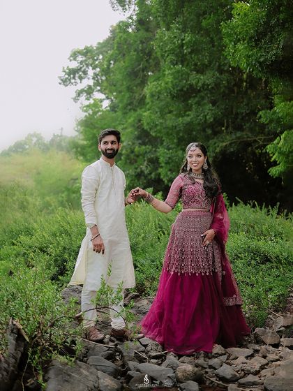 A lovely portrait with the couple holding hands against a misty, green backdrop. Their traditional attire adds a touch of elegance.