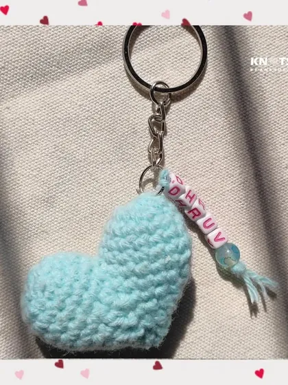 A simple and sweet light blue crochet heart keychain, personalized with the name "Dhruv" on beaded letters.
