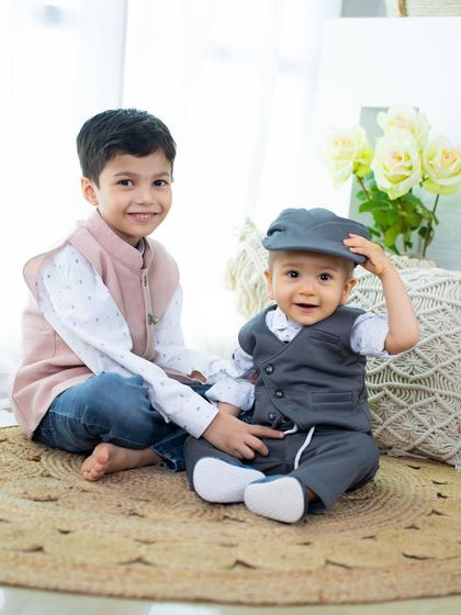 A playful moment between two brothers. The little one tipping his hat adds a touch of adorable charm to this sibling portrait.