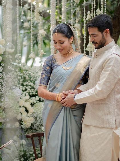 A beautiful moment from a wedding ceremony, with the couple framed by an abundance of white flowers and delicate baby's breath.