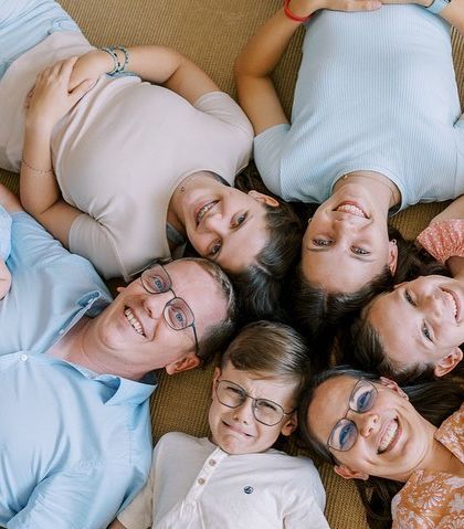 A fun, unconventional family portrait lying on the floor. I use prompts and games to get genuine emotions and create memorable, unique images.