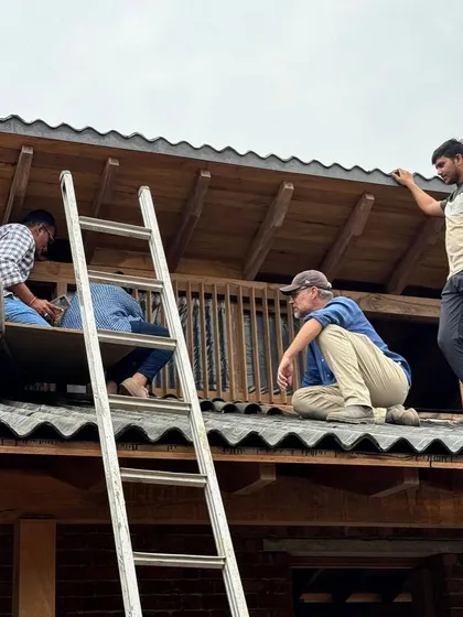Working out the details of the roof structure requires on-site collaboration. Here, our team is perched on the corrugated roofing, discussing the finer points of the joinery and waterproofing.