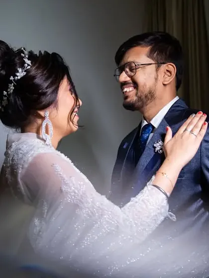 A beautiful, candid moment of shared laughter between the bride and groom, captured with a creative light flare for an artistic touch.