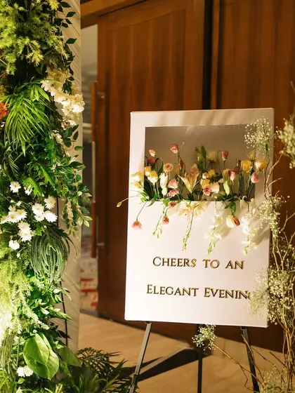 "Cheers to an Elegant Evening." This custom welcome sign, featuring a unique 3D floral shadow box design, was the first thing guests saw, setting the tone for a sophisticated and memorable night.