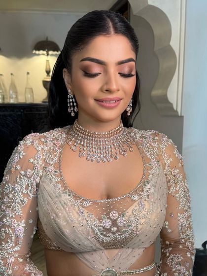 A close-up of the bride's makeup, her hair pulled back in a sleek half-ponytail with glossy waves.