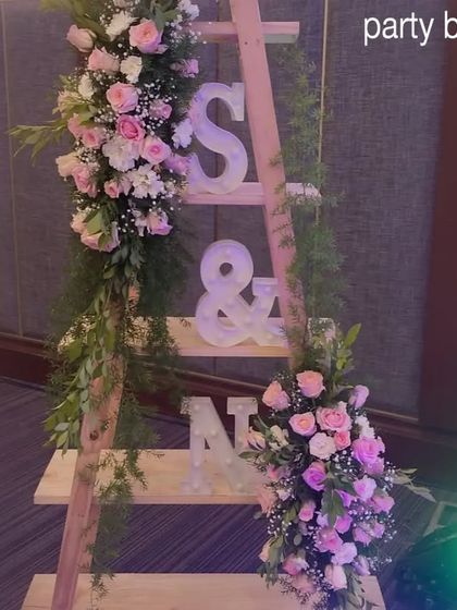 A decorative ladder displaying the couple's initials, adorned with flowers. This is a unique and personal touch we love to add to anniversary celebrations.
