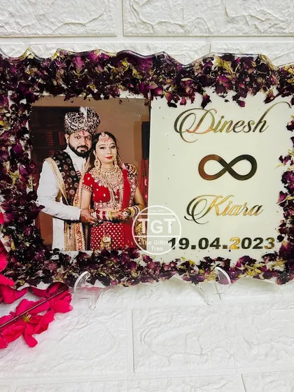 A clear, frontal view of the frame with dark purple flowers, highlighting the contrast with the white background and gold text.