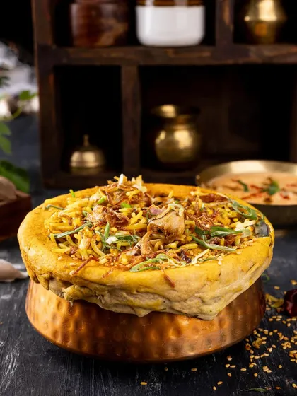 A dum-pukht biryani, with the dough seal still intact. This shot creates a sense of anticipation and authenticity, showing the traditional cooking method.