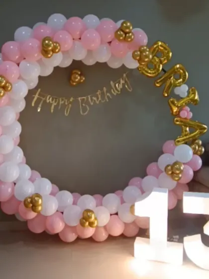 A sweet and simple ring decoration for a 13th birthday. The pink, white, and gold color scheme, along with the marquee number, creates an elegant look for a teen's party at home.