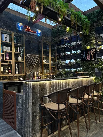 Your backyard bar, reimagined. We combined a vertical garden, hanging plants, and sleek materials to create this luxurious outdoor bar, perfect for entertaining in style.