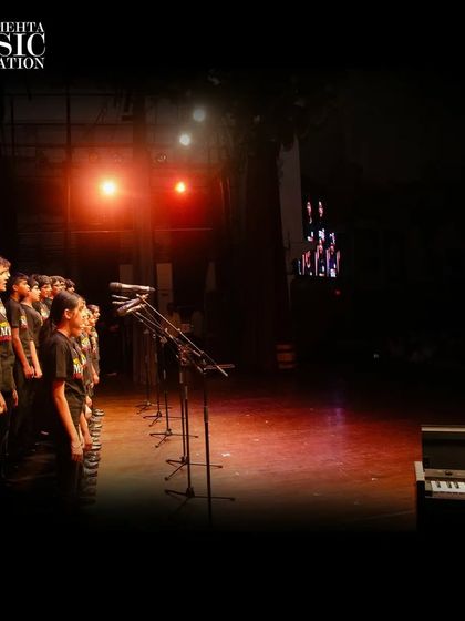 A wide shot of the choir on a professionally lit stage with microphones, showcasing the high-quality performance experiences we provide.