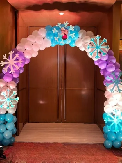 We created this enchanting Frozen-themed entrance arch to welcome guests to a winter wonderland event. The arch uses a mix of blue, white, and purple balloons, accented with snowflake cutouts and life-sized character standees of Elsa and Anna.