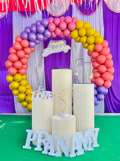 A rainbow-themed balloon arch for a birthday party. The bright colors like pink, yellow, and purple are perfect for a fun and cheerful celebration.