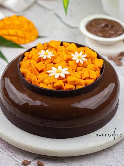 My Mango Chocolate entremet combines the tropical sweetness of mango with the deep, rich flavor of Belgian chocolate. The glossy chocolate glaze and the pool of fresh mangoes on top make it a truly decadent treat.