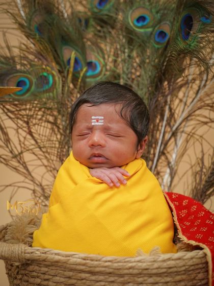 A simple, serene portrait without the crown, focusing on the baby's peaceful expression against the peacock feathers.