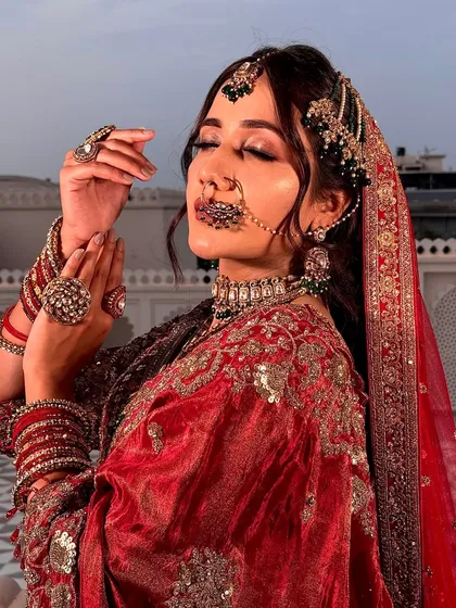 A moment of royal contemplation. This shot highlights the intricate jewelry and the soft, blended makeup that enhances the bride's features for a truly regal feel.