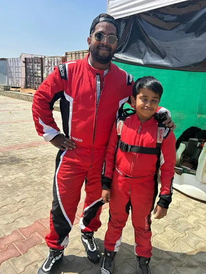A coach and young driver in matching red race suits.