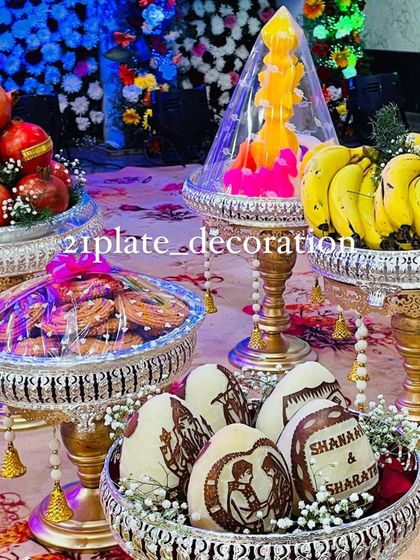 A beautiful display of plate decorations, including custom-carved coconuts and a variety of sweets and fruits. The colorful lighting adds a festive touch to the setup.