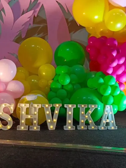 A close-up of the marquee letters for a Barbie-themed party, with colorful balloon clusters in the background.