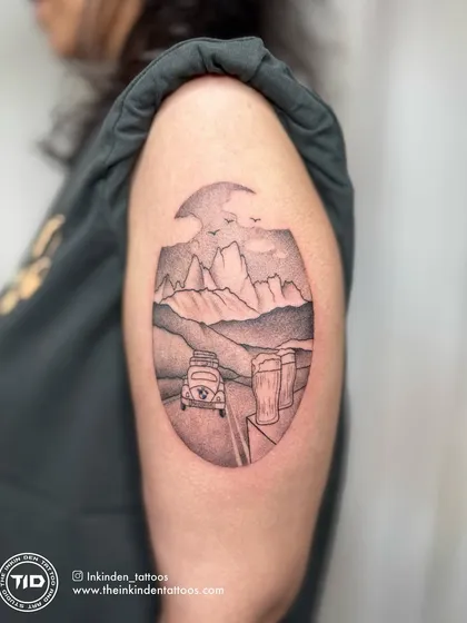 A stipple-shaded travel tattoo depicting a road trip through the mountains. The dotwork technique gives it a unique, vintage feel.