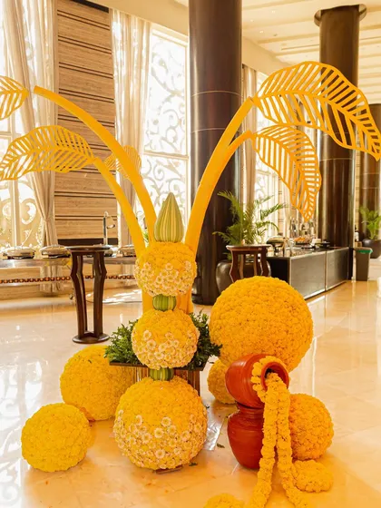 A beautiful floral centerpiece for a sunflower-themed Haldi, featuring marigold balls and leaf-cutout structures. Every detail is designed to match the sunny and cheerful theme.