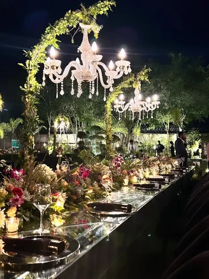 An enchanting sit-down dinner under the stars. We designed this intimate gathering with long, mirrored tables reflecting the glow of bespoke floral runners and cascading crystal chandeliers wrapped in fresh greenery. 🌸