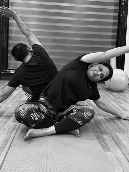 This black and white photo captures the beautiful symmetry of a partner side-stretch. This is a great way to improve flexibility in the side body while practicing with a friend or family member at home.