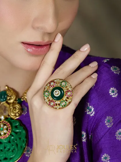 An Aalayaa ring that celebrates beauty. This large, circular ring features a central emerald surrounded by intricate enamel and polki work.
