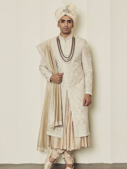 The full view of the Angarkha sherwani reveals its unique, overlapping silhouette. This traditional cut is given a modern update with fine tailoring and luxurious fabric.