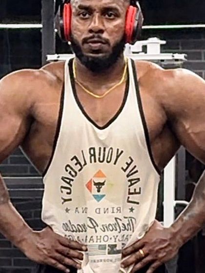 Posing in the gym, this client displays the powerful physique he built through a high-carb, carb-cycling diet and intense training.