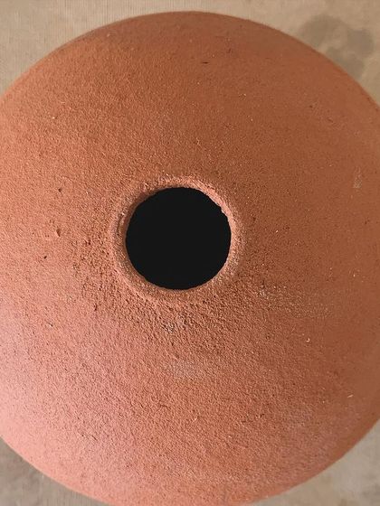 A top-down view of a raw terracotta vase, showing its perfect circular opening.