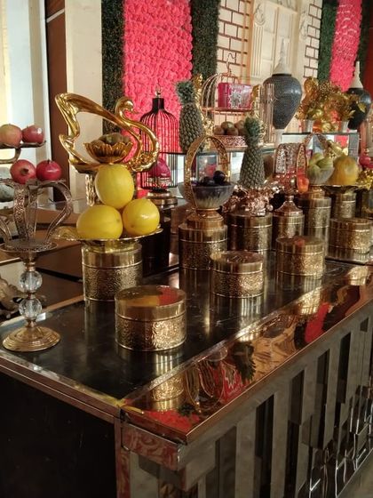 An elaborate fruit and salad bar with a polished black countertop and golden accents. This display features a variety of fresh fruits and decorative items, serving as a healthy and beautiful part of the menu.
