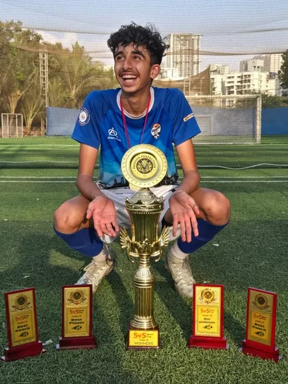 A player celebrates with his impressive collection of individual and team trophies after a successful U15 tournament.
