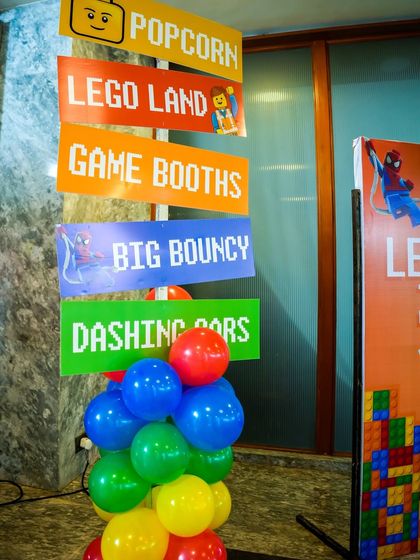 A LEGO-themed signpost pointing the way to "Popcorn," "Lego Land," "Game Booths," and "Dashing Cars."