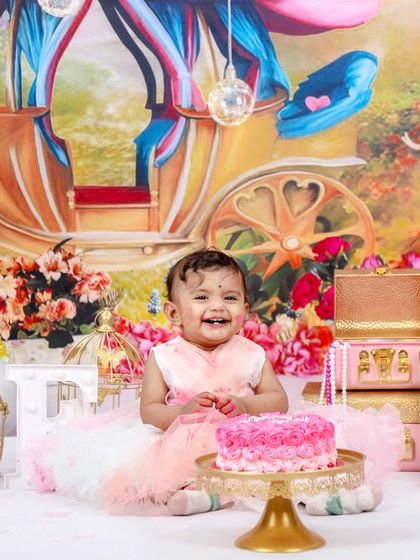 A fairytale first birthday for a little princess. This elaborate setup features a royal carriage backdrop, a pink castle cake, and plenty of sparkle for a magical celebration.