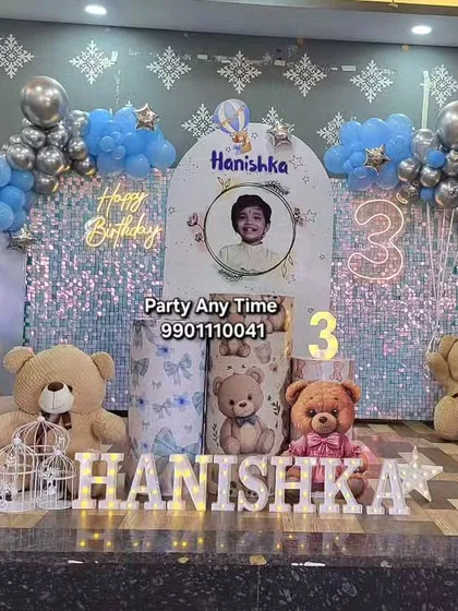 This is my complete teddy bear theme for a 3rd birthday party. It includes a custom backdrop with a photo, a shimmer wall, a balloon arch in blue and silver, themed plinths for the cake, and light-up marquee letters for the name. I also provide the large teddy bears to complete the look.