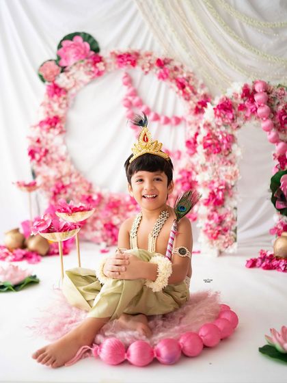 A happy little Kanha enjoying his photoshoot, surrounded by pink lotuses and pearls.