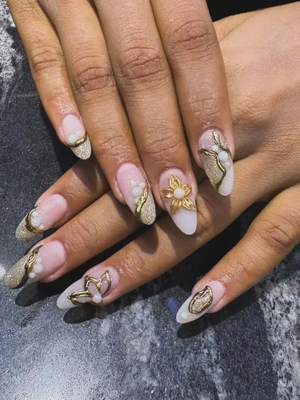 We love adding dimension to our nail art. This design features intricate 3D metallic gold floral and butterfly embellishments over a soft, shimmery base, creating a luxurious and textured look that is truly one-of-a-kind.