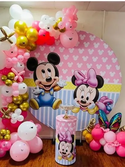A Mickey and Minnie Mouse themed party with a custom backdrop and balloon arch in pink, white, and gold.