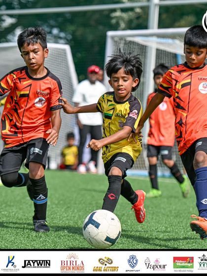 A young player shields the ball under pressure during the intense U9 final. We train our players to be strong and composed in possession.