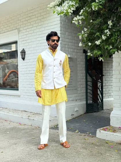 Make a vibrant statement at your next Haldi or Sangeet ceremony. This bright yellow patterned kurta is layered with a crisp white Nehru jacket, creating a look that is both festive and dapper.